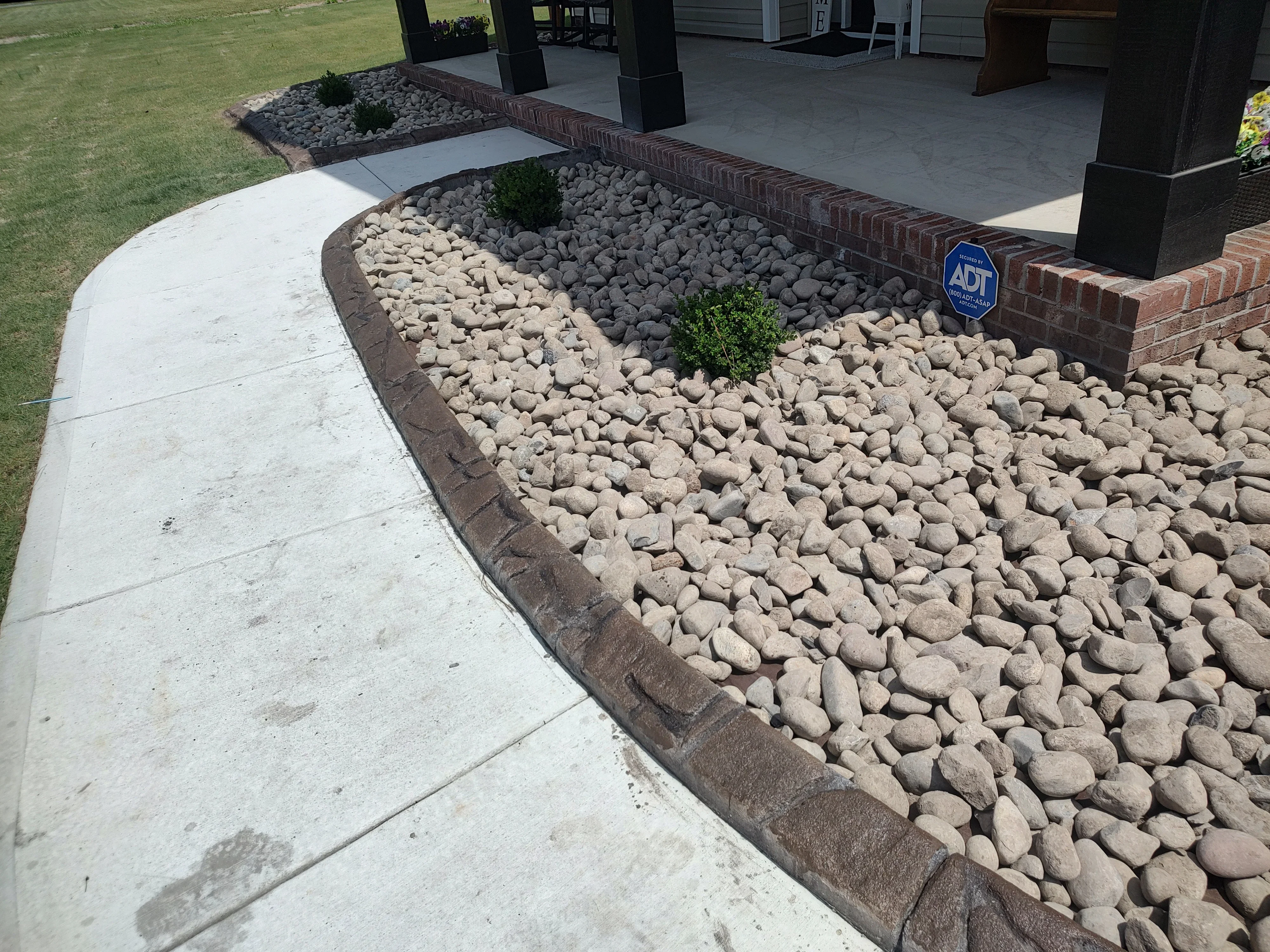 Close-up of curved concrete curbing along a rock-filled garden bed and walkway