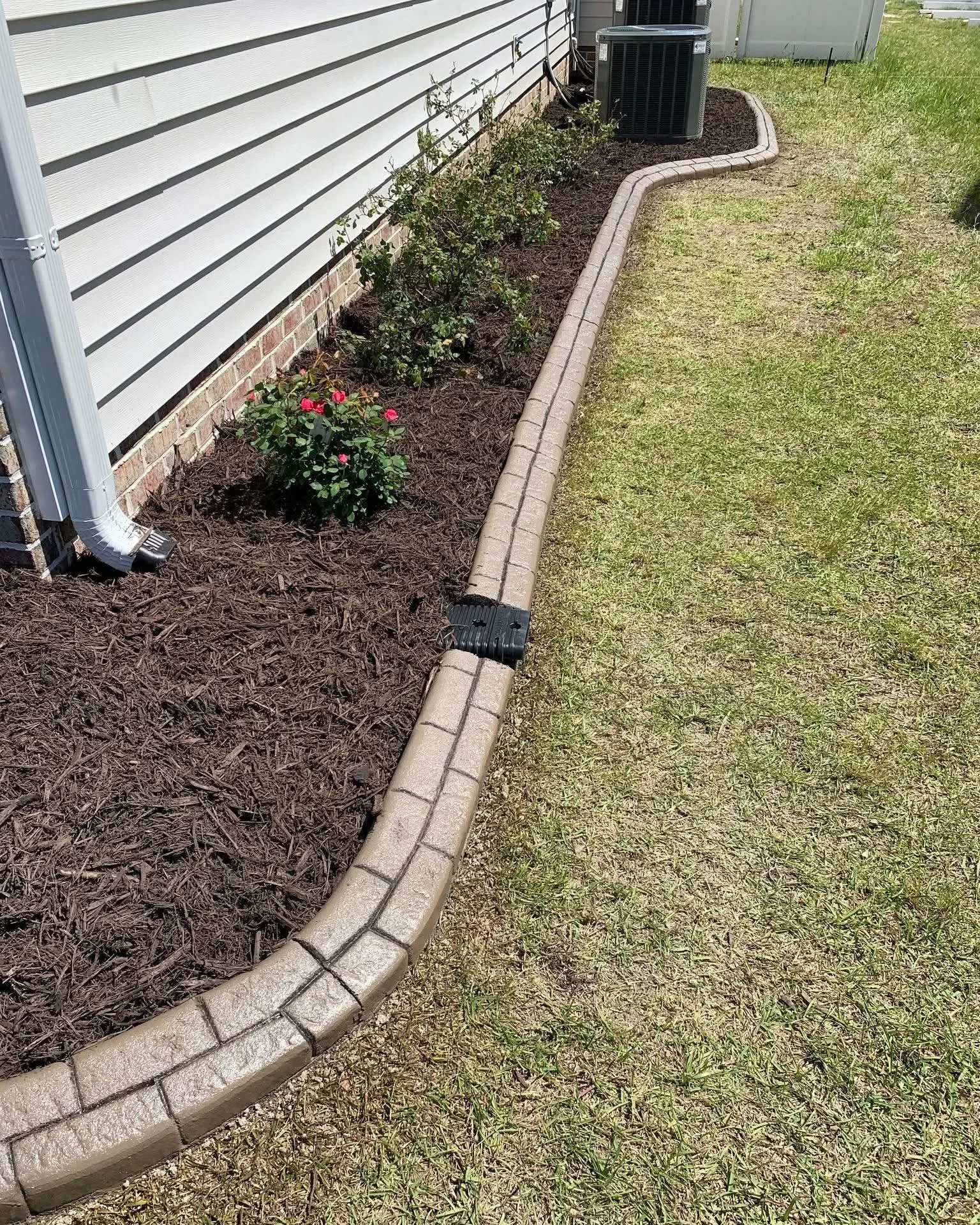Textured concrete curbing containing mulch in a residential planting bed