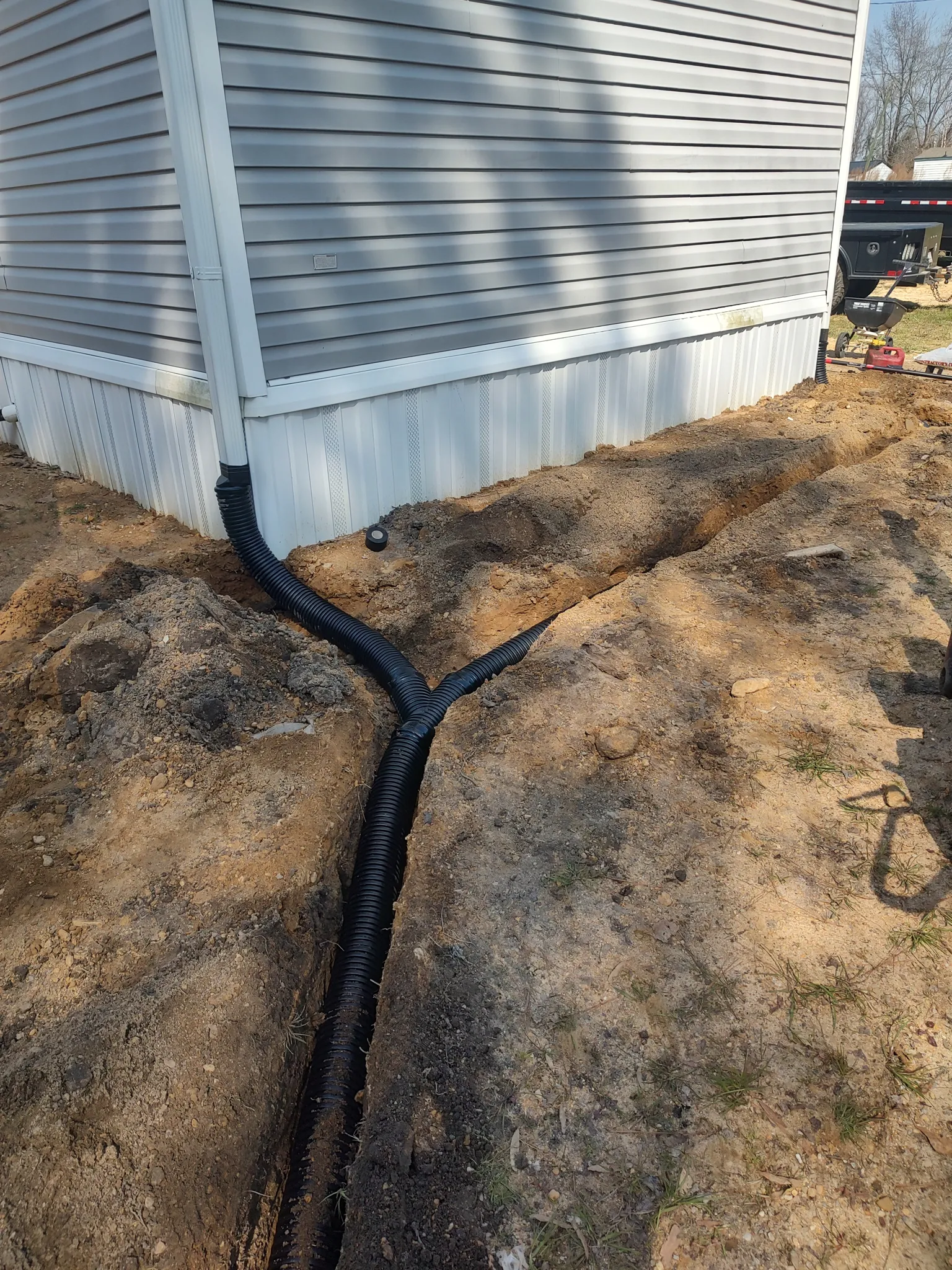 Buried gutter extension pipes joined in a trench to carry roof water away from the house