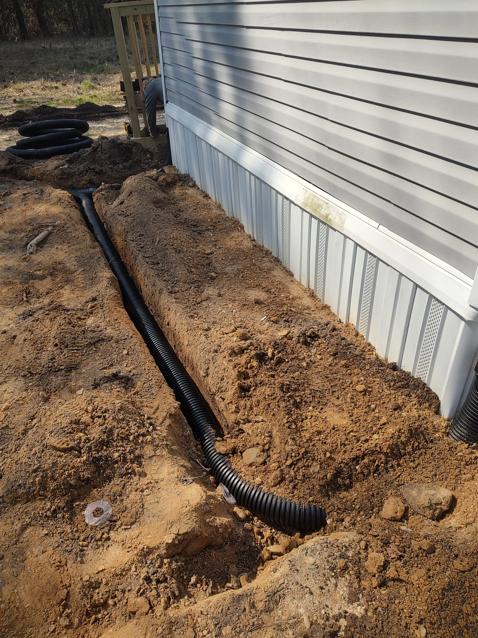 Corrugated drain pipe in a trench routing downspout water away from a home's foundation
