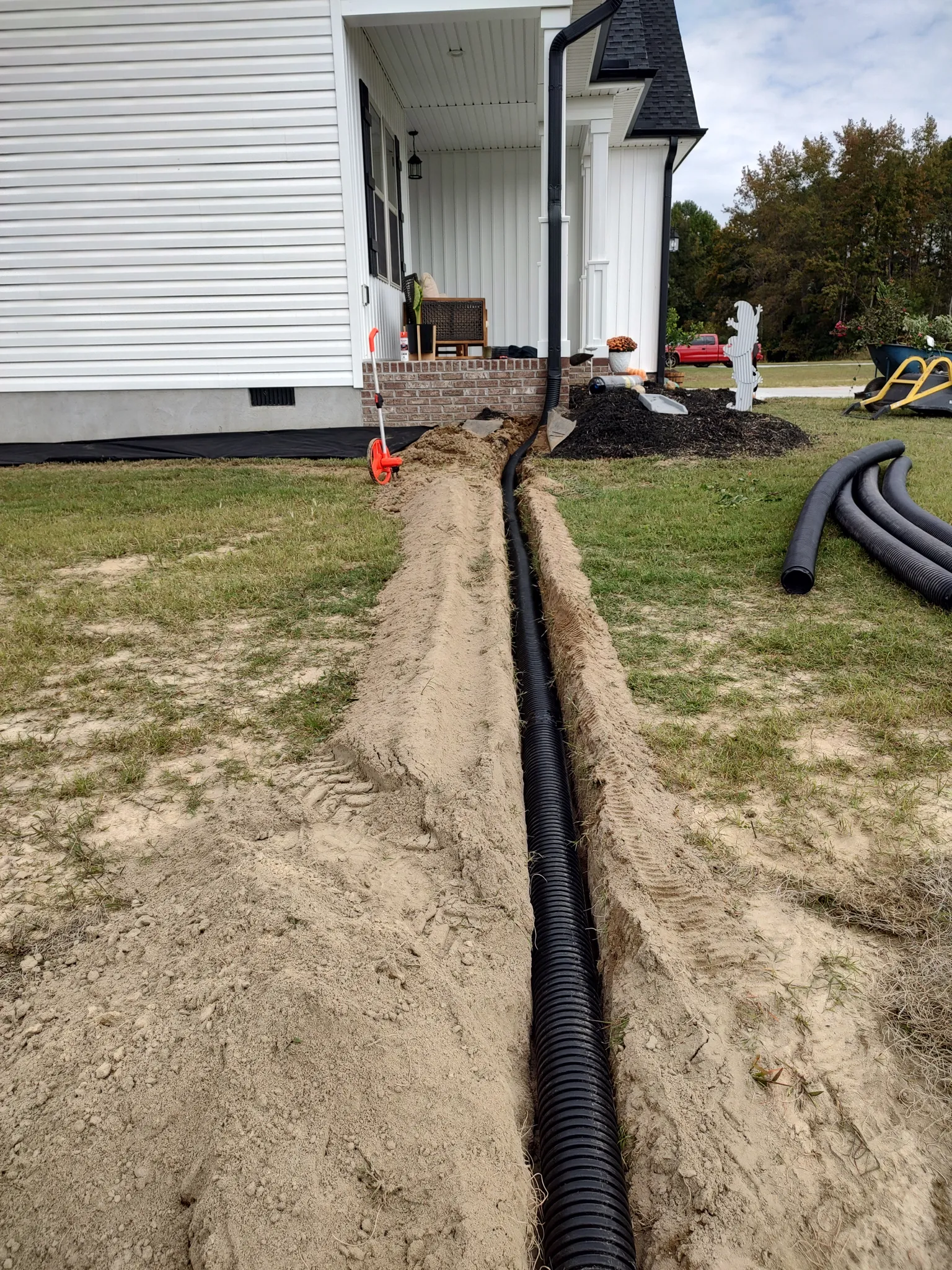Drainage pipe installed in an open trench running from a home's downspouts across the lawn