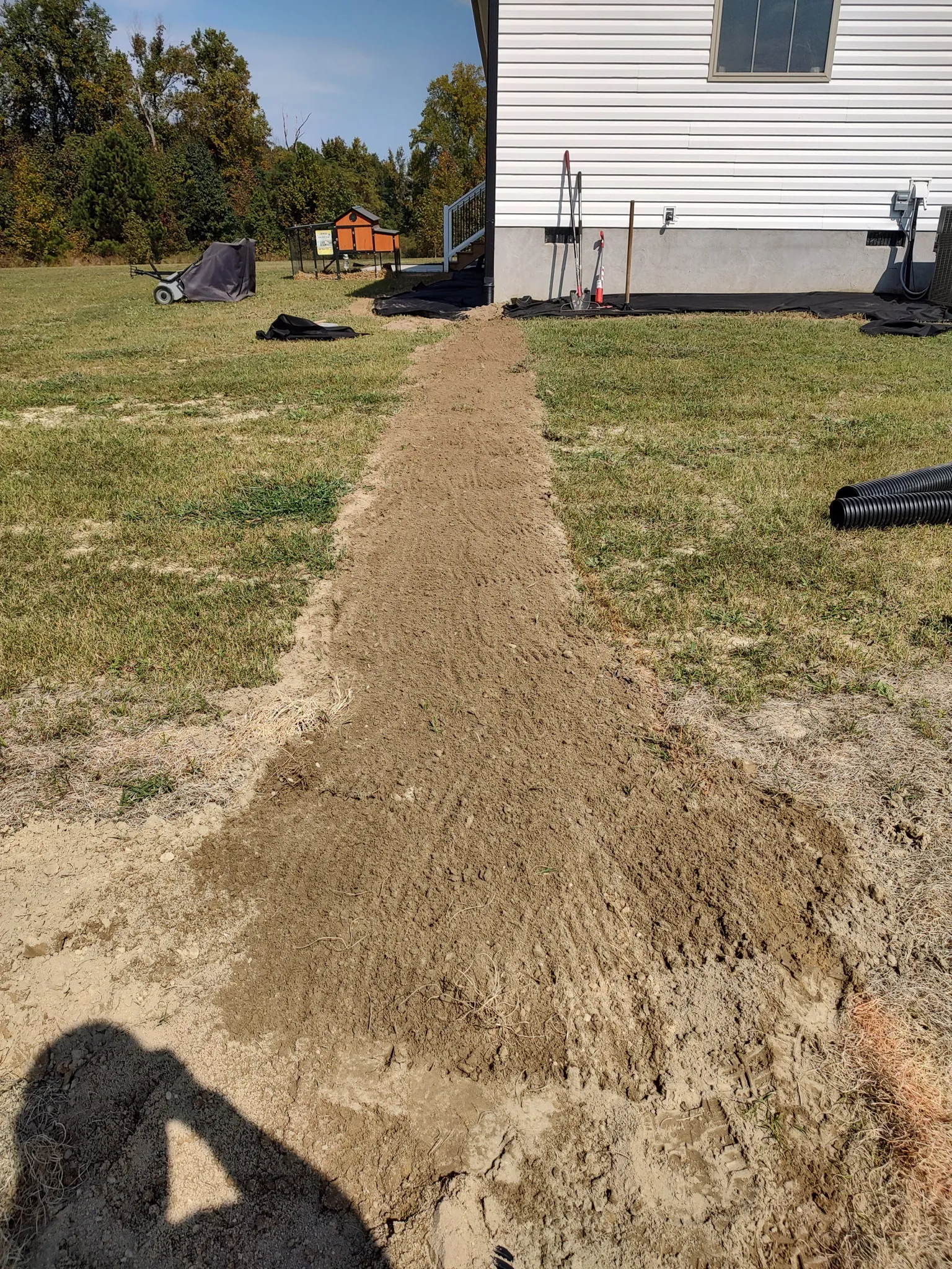Backfilled drainage trench running across a lawn after installation