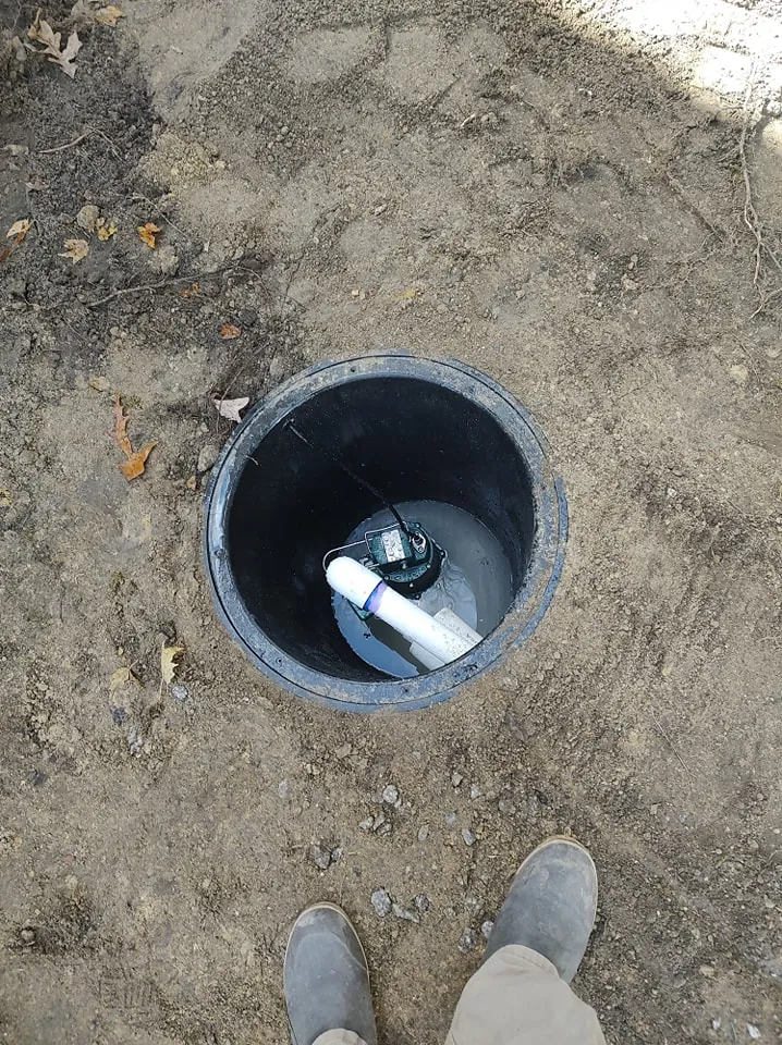 Outdoor sump pump basin installed in the ground with discharge piping in place