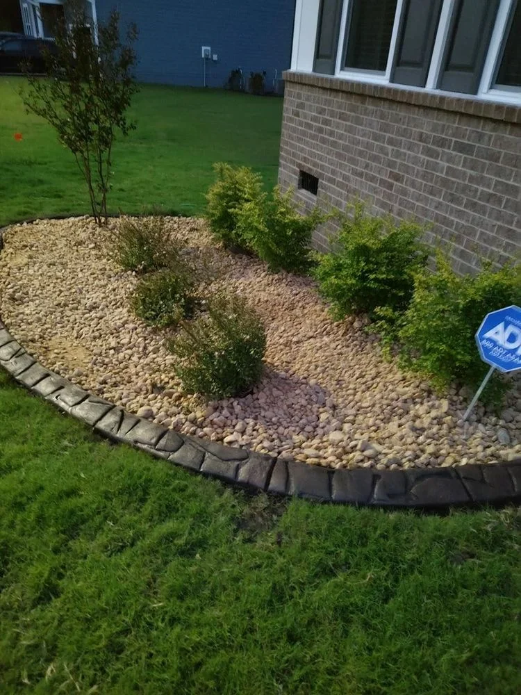 Natural stone finish concrete curbing around a residential landscape planting bed