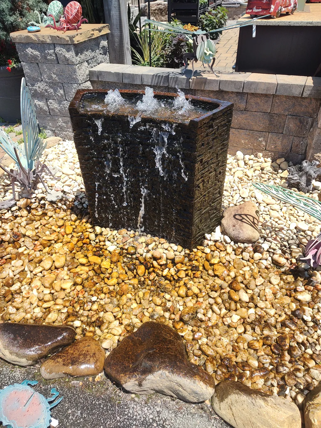 A pondless bubbling fountain running over stone in a landscaped bed