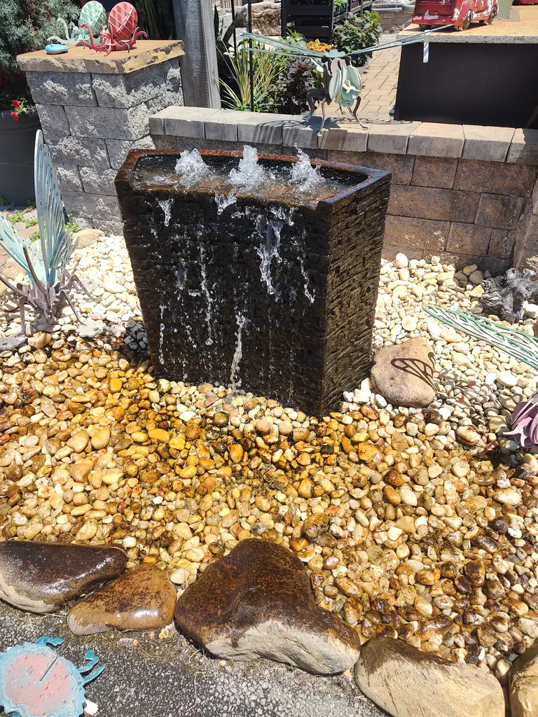 A pondless bubbling fountain running over stone in a landscaped bed