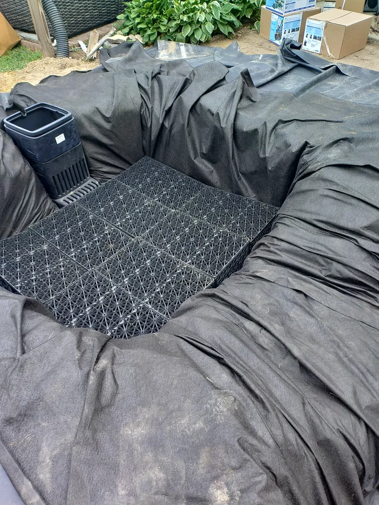 The pump and plumbing being installed in a lined koi pond during construction