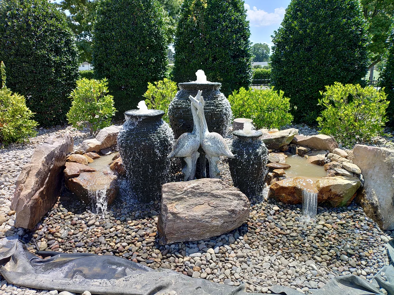 A tiered garden fountain with songbirds perched on the rim, built by Landscaping Plus LLC in eastern NC