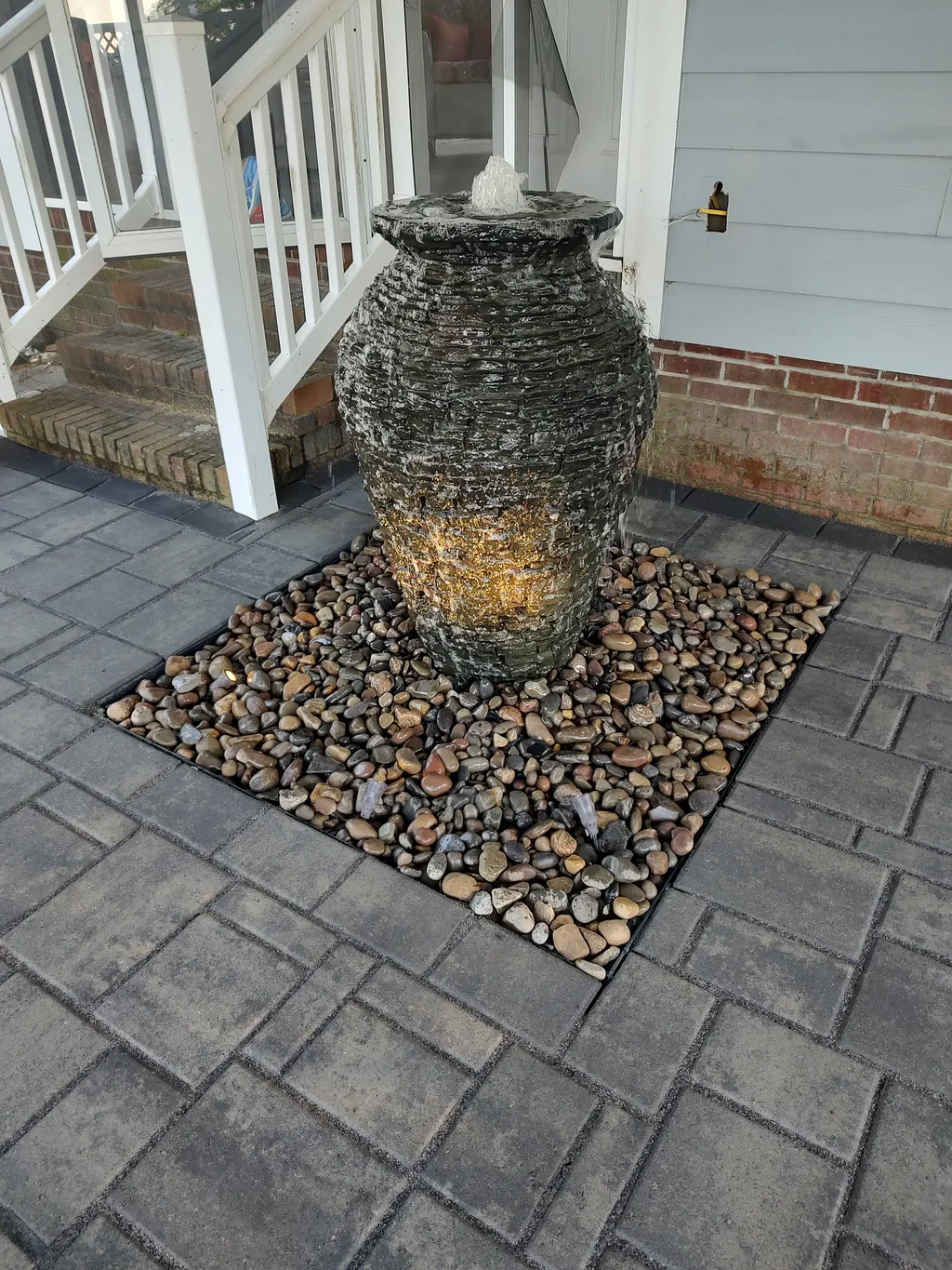 A compact bubbling fountain feature set into a stone and gravel bed
